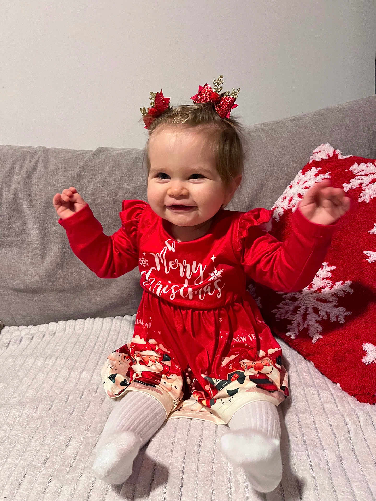 Alice a rejoint le concours — aidez-le/la à gagner de superbes lots ! baby, child, christmas, red_dress, happy, smiling, hair_bows, couch, pillow, holiday, festive, indoor, tights, sitting, cute, face, person, celebration, christmas_decor, winter