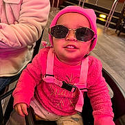Lusiana is registered to the contest to win money with this photo: toddler, child, sunglasses, pink_beanie, pink_sweater, high_chair, indoor, flooring, person, fashion, cute, smile, clothing, seat, hand, pants, footwear, baby, accessory, casual