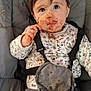 child, toddler, messy, face_paint, food_smear, high_chair, straps, clothing, floral_pattern, indoor, curious_expression, brown_hair, long_sleeves, pants, seat, baby, cute, portrait, messy_hands, young_child