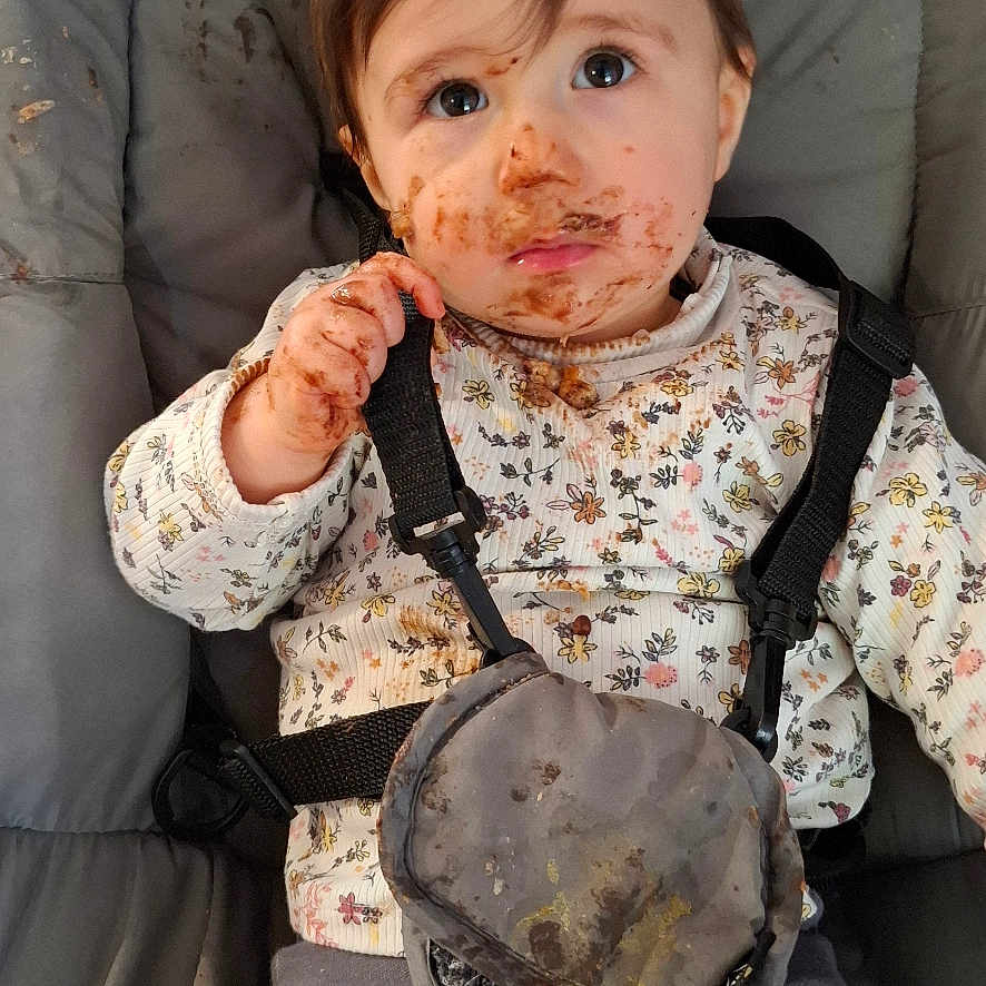 Jade a rejoint le concours — aidez-le/la à gagner de superbes lots ! baby, brown_hair, child, clothing, curious_expression, cute, face_paint, floral_pattern, food_smear, high_chair, indoor, long_sleeves, messy, messy_hands, pants, portrait, seat, straps, toddler, young_child