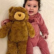 Paola a rejoint le concours — aidez-le/la à gagner de superbes lots ! baby, big_eyes, blanket, chubby_cheeks, close_up, cute, hair, happy, indoor, infant, lying_down, onesie, pink_clothing, plush_toy, portrait, smiling, soft_texture, stuffed_animal, teddy_bear, toddler