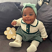 Eliana-Brielle joined the competition — help win amazing prizes! baby, child, smiling, headband, knitted_sweater, couch, pillow, indoor, portrait, cute, white_booties, green_skirt, happy, young_child, infant, sitting, face, home, soft_lighting, decor