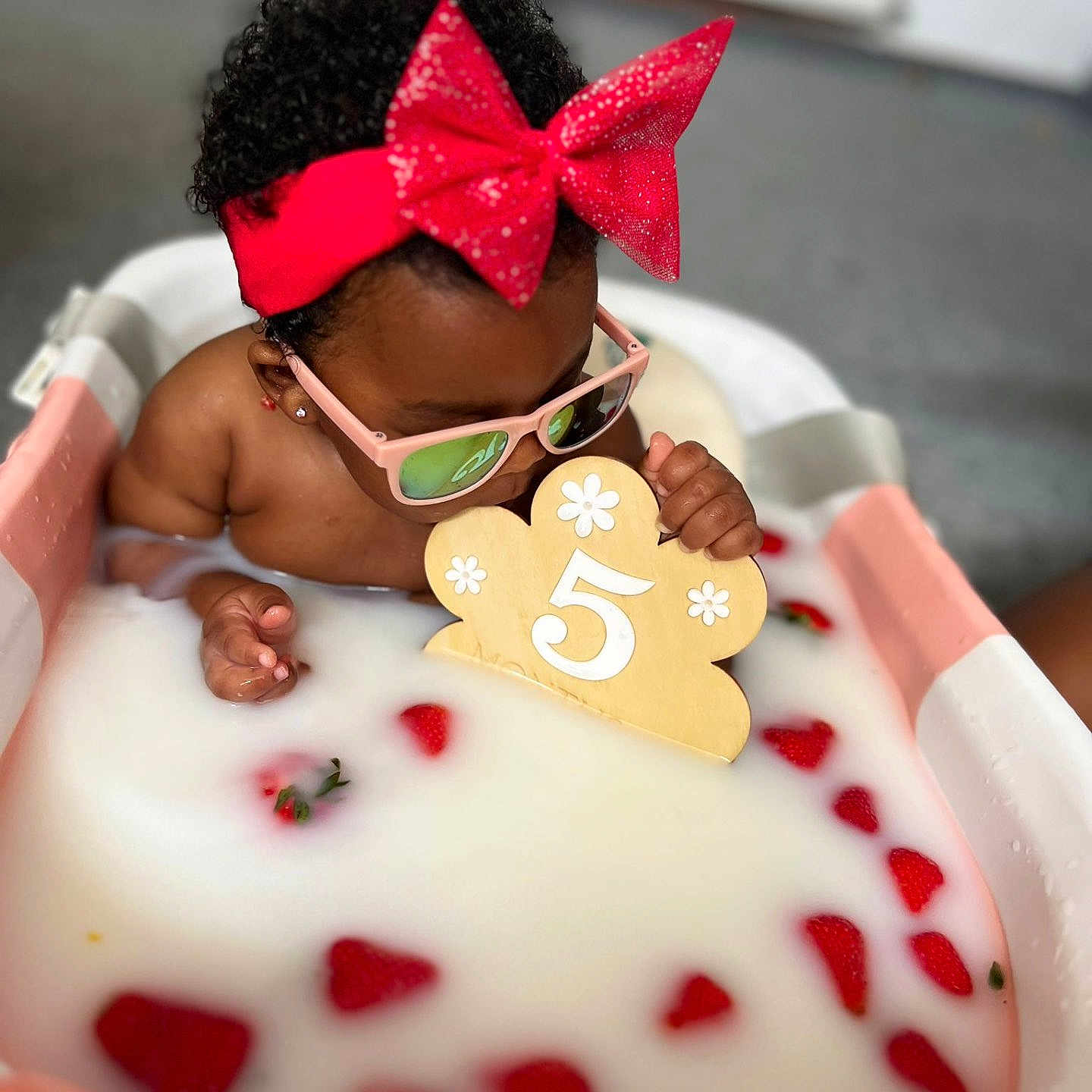 Eliana-Brielle is registered to the contest to win money with this photo: baby, bathtub, celebration, child, cute, fruit, headband, indoor, milk, milk_bath, number_5, pink_sunglasses, playful, portrait, red_bow, relaxing, strawberries, toddler, water, wooden_sign