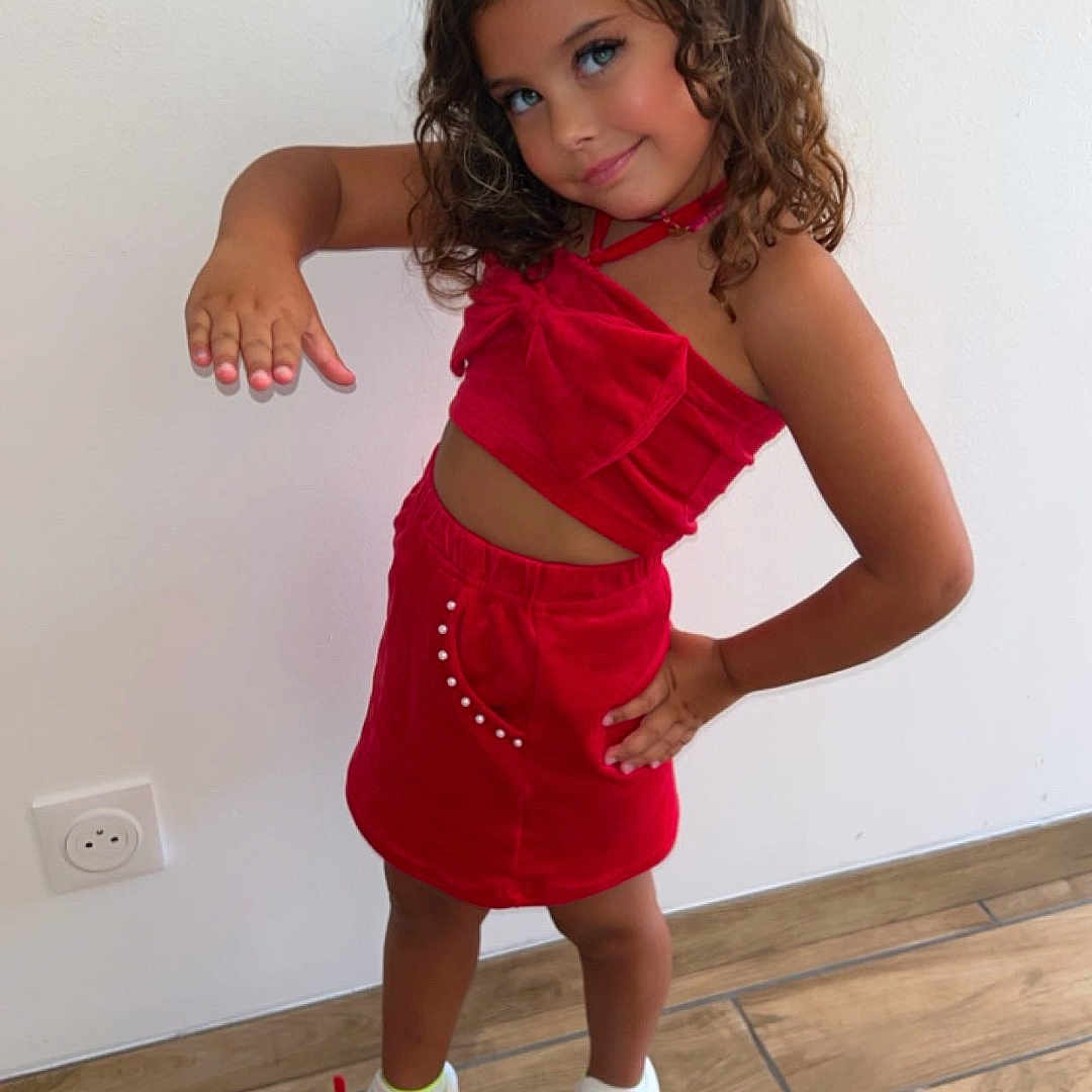 Hatlanna participe au concours pour gagner de l'argent avec cette photo : accessories, casual, child, curly_hair, cute, fashion, girl, happy, indoor, mischievous, modern, playful, portrait, pose, red_clothing, smile, sneakers, standing, white_wall, wooden_floor