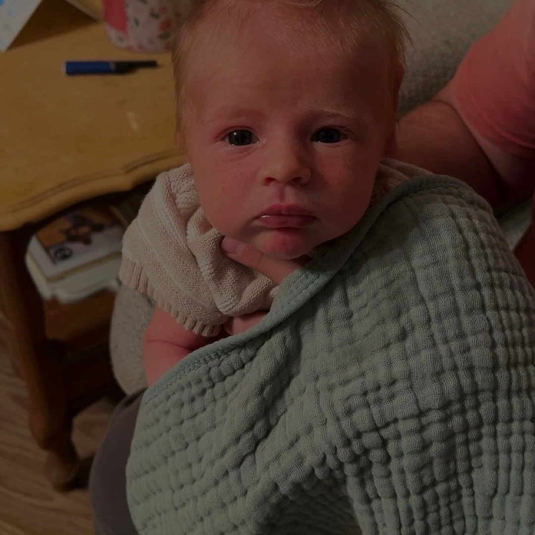 Wade is registered to the contest to win money with this photo: baby, blanket, clothing, couch, cushion, face, furniture, hardwood, head, homedecor, knitwear, pants, pen, person, photoframe, photography, portrait, sitting, sweater, wood