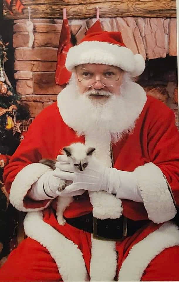 Judy is registered to the contest to win money with this photo: beard, christmas, christmas_eve, event, eye, facial_hair, fictional_character, fur, glove, hat, holiday, human_body, lap, natural_material, photograph, red, santa_claus, sleeve, smile, white