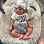 baby, infant, baby_seat, plush_toys, zebra_toys, hat, nike_shirt, footwear_absent, patterned_fabric, baby_clothing, baby_bouncer, flooring, foot, indoor, soft_toys, baby_face, baby_feet, baby_hands, baby_hat, baby_gaze