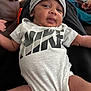 Micah Jackson joined the competition — help win amazing prizes! baby, infant, clothing, onesie, hat, beanie, indoor, couch, television, person, smile, face, arm, leg, relaxing, casual, nike, home, child, cute