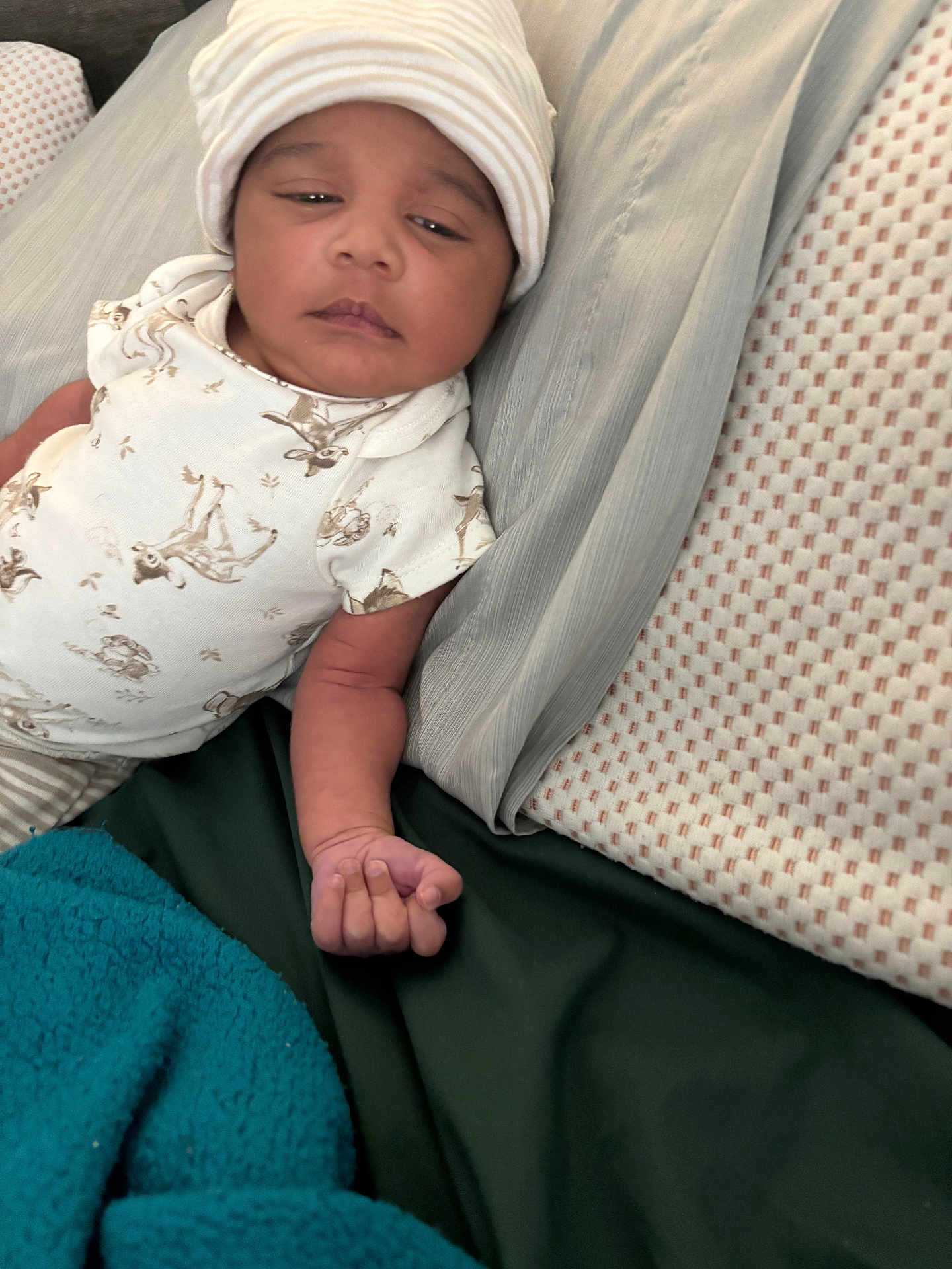 Micah Jackson is registered to the contest to win money with this photo: baby, infant, hat, onesie, bed, blanket, pillow, sleepy, lying_down, child, person, furniture, textile, pattern, skin, hand, portrait, indoors, cute, resting