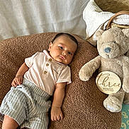Isaiah joined the competition — help win amazing prizes! baby, infant, teddy_bear, blanket, clothing, striped_shorts, soft_toy, wooden_sign, three_months, lying_down, indoor, cute, calvin_klein, cozy, portrait, child, smile, person, fabric, comfort