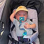 Elyo a rejoint le concours — aidez-le/la à gagner de superbes lots ! baby, pacifier, hat, stroller, child, infant, striped_clothing, blue_shorts, safety_harness, relaxed, seat, casual, cute, outdoor, sunlight, portrait, person, baby_accessory, comfort, infant_care