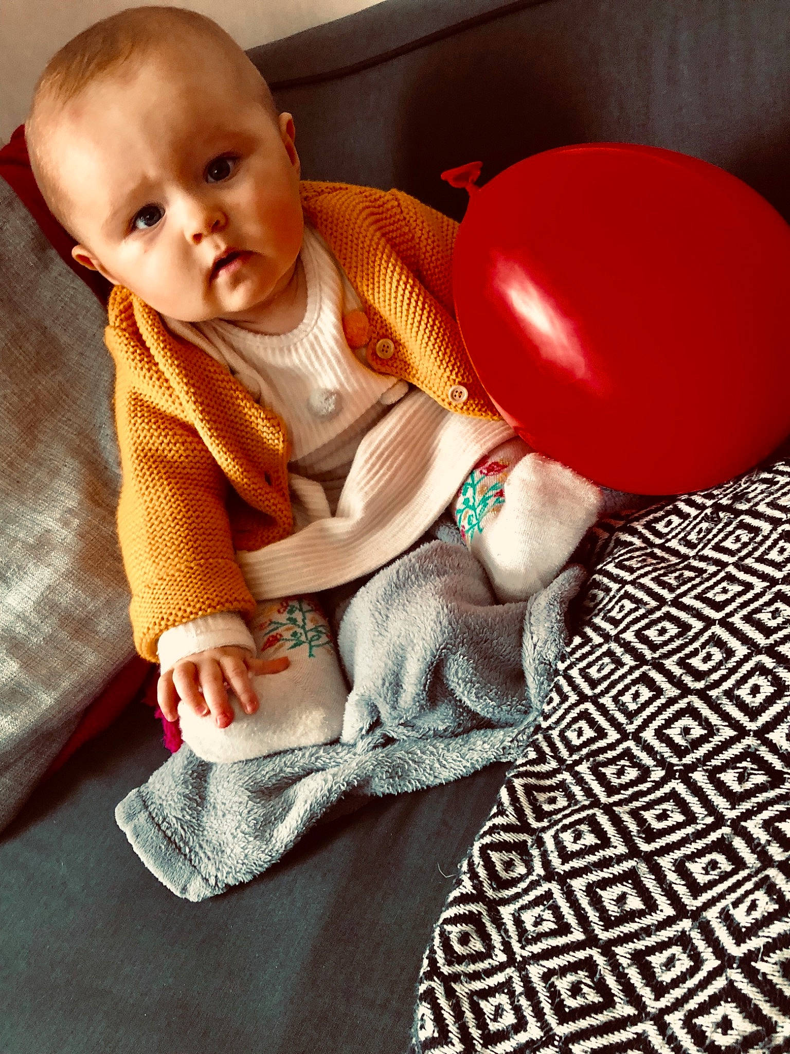 Maddy a rejoint le concours — aidez-le/la à gagner de superbes lots ! baby, balloon, child, outerwear, person, play, red, sitting, sleeve, smile, t_shirt, toddler