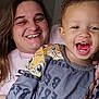 Weston is registered to the contest to win money with this photo: child, toddler, woman, smile, laughing, indoors, clothing, bottle, sippy_cup, person, face, hair, joy, happy, curly_hair, casual, seated, parent_child, family, playful