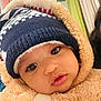 baby, child, face, hat, knit_hat, winter_clothing, onesie, fluffy, indoor, curious, closeup, portrait, warm, soft_texture, cute, young_child, apparel, headwear, expression, person
