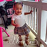 toddler, child, porch, smiling, plaid_skirt, boots, white_tshirt, hair_buns, stroller, car, railing, outdoor, concrete_floor, pink, love_text, happy, cute, playful, daylight, person