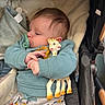 baby, pacifier, giraffe_toy, stroller, blue_sweater, patterned_pants, blanket, infant, child, cute, soft, cozy, toy, clothing, seat, comfort, sleepy, indoors, person, young_child