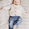 baby, child, infant, lying_down, white_vest, blue_jeans, barefoot, fluffy_blanket, texture, cute, portrait, smiling, cozy, indoors, small_hands, small_feet, casual_clothing, happy, young, person