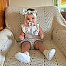 Astrid is registered to the contest to win money with this photo: baby, child, pacifier, headband, bow, armchair, crochet, blanket, indoors, smile, face, legs, clothing, socks, footwear, person, seated, cute, infant, portrait