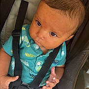 Brandon is registered to the contest to win money with this photo: baby, child, car_seat, safety_harness, teal_shirt, dinosaur_print, curious, hands, infant, seat, straps, young_child, portrait, close_up, indoors, cute, face, expression, clothing, person