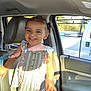 child, toddler, smiling, inside_car, sunlight, curly_hair, striped_top, frills, happy, seat, car_door, window, shadow, daylight, person, portrait, clothing, young_child, cute, bright
