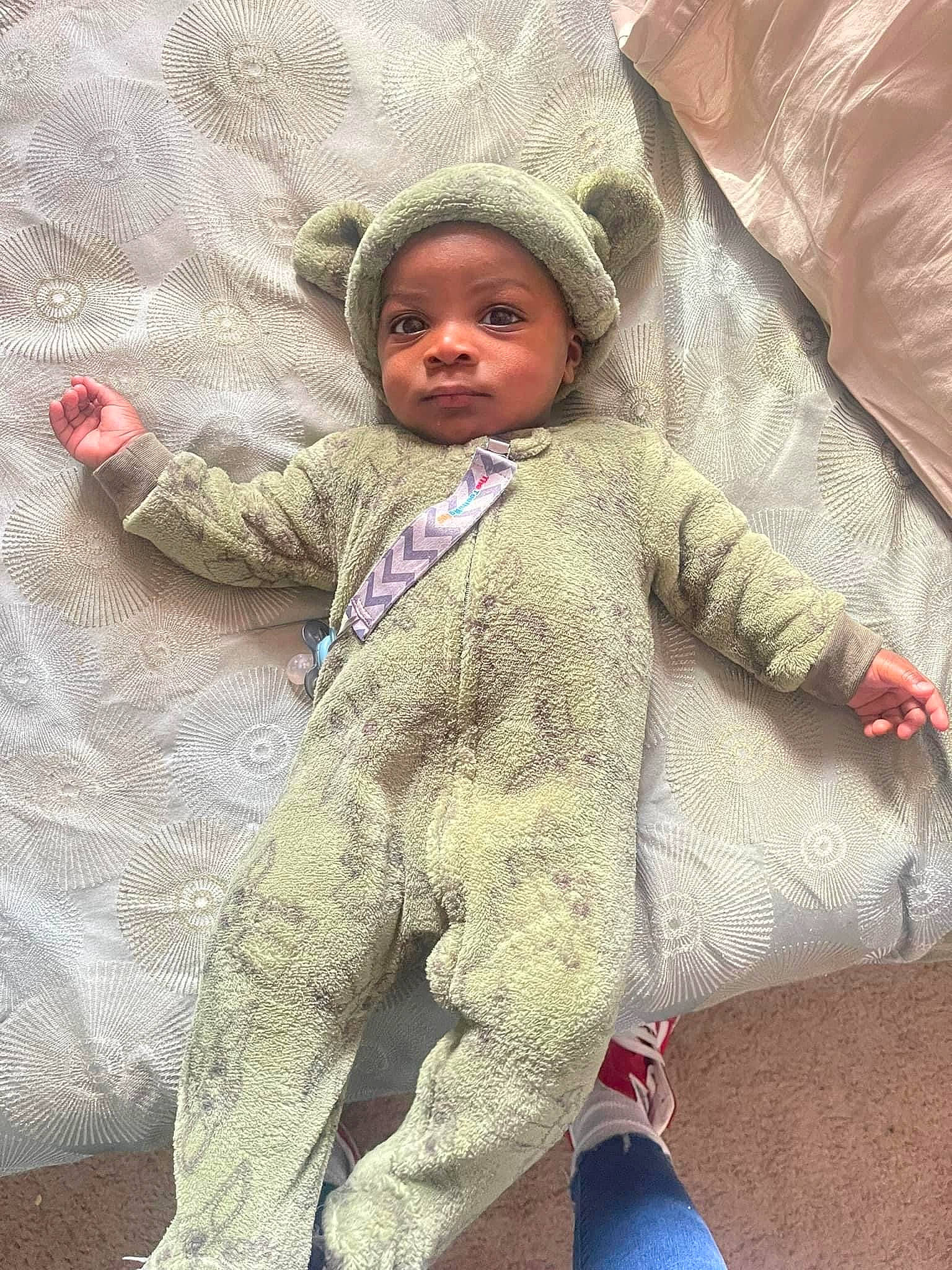 Messiah is registered to the contest to win money with this photo: baby, baby_toddler_clothing, bedding, child, comfort, face, flooring, fun, fur, headwear, linens, pattern, person, polar_fleece, room, skin, sleeve, toddler, wool, woolen