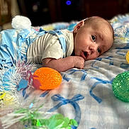 Hudson joined the competition — help win amazing prizes! baby, infant, blanket, easter_eggs, glitter, colorful, garland, soft_toys, cute, portrait, indoors, laying_down, clothing, white_shirt, blue_outfit, decorations, holiday, celebration, face, expression
