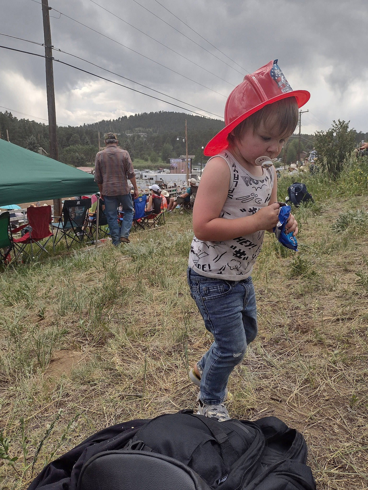 Jayson is registered to the contest to win money with this photo: automotive_tire, chair, cloud, fun, grass, grassland, hat, jeans, landscape, leisure, luggage_and_bags, person, recreation, shorts, sky, soil, sun_hat, t_shirt, tent, toddler