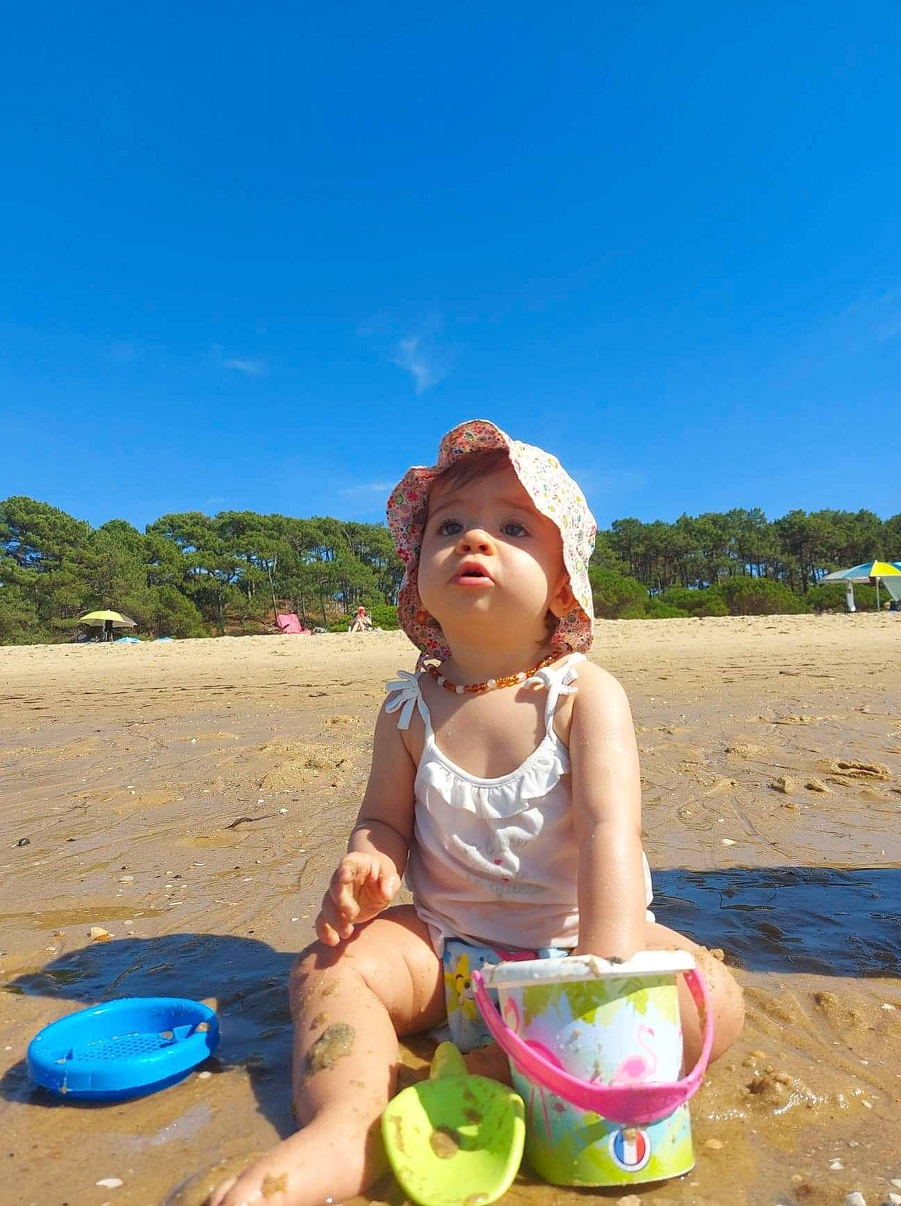 Nella a rejoint le concours — aidez-le/la à gagner de superbes lots ! beach, child, fun, happy, hat, headwear, holiday, landscape, leisure, ocean, people_in_nature, people_on_beach, person, recreation, sand, sitting, sky, summer, sunlight, toddler
