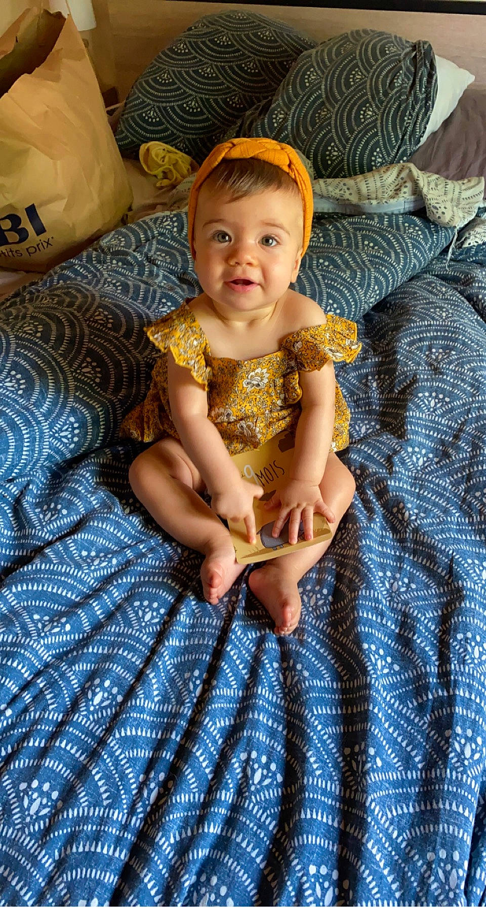 Nella participe au concours pour gagner de l'argent avec cette photo : abdomen, baby, baby_toddler_clothing, cheek, child, comfort, eye, finger, hand, happy, head, human_leg, linens, pattern, person, sitting, skin, smile, textile, toddler