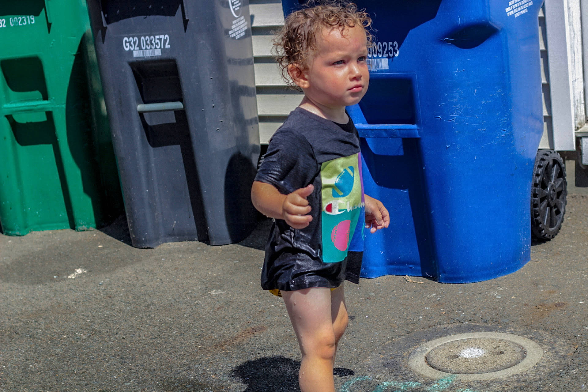 John is registered to the contest to win money with this photo: asphalt, automotive_tire, blue, child, electric_blue, fun, gas, green, human_leg, leisure, person, play, recreation, shorts, standing, t_shirt, tire, toddler, waste_containment, water