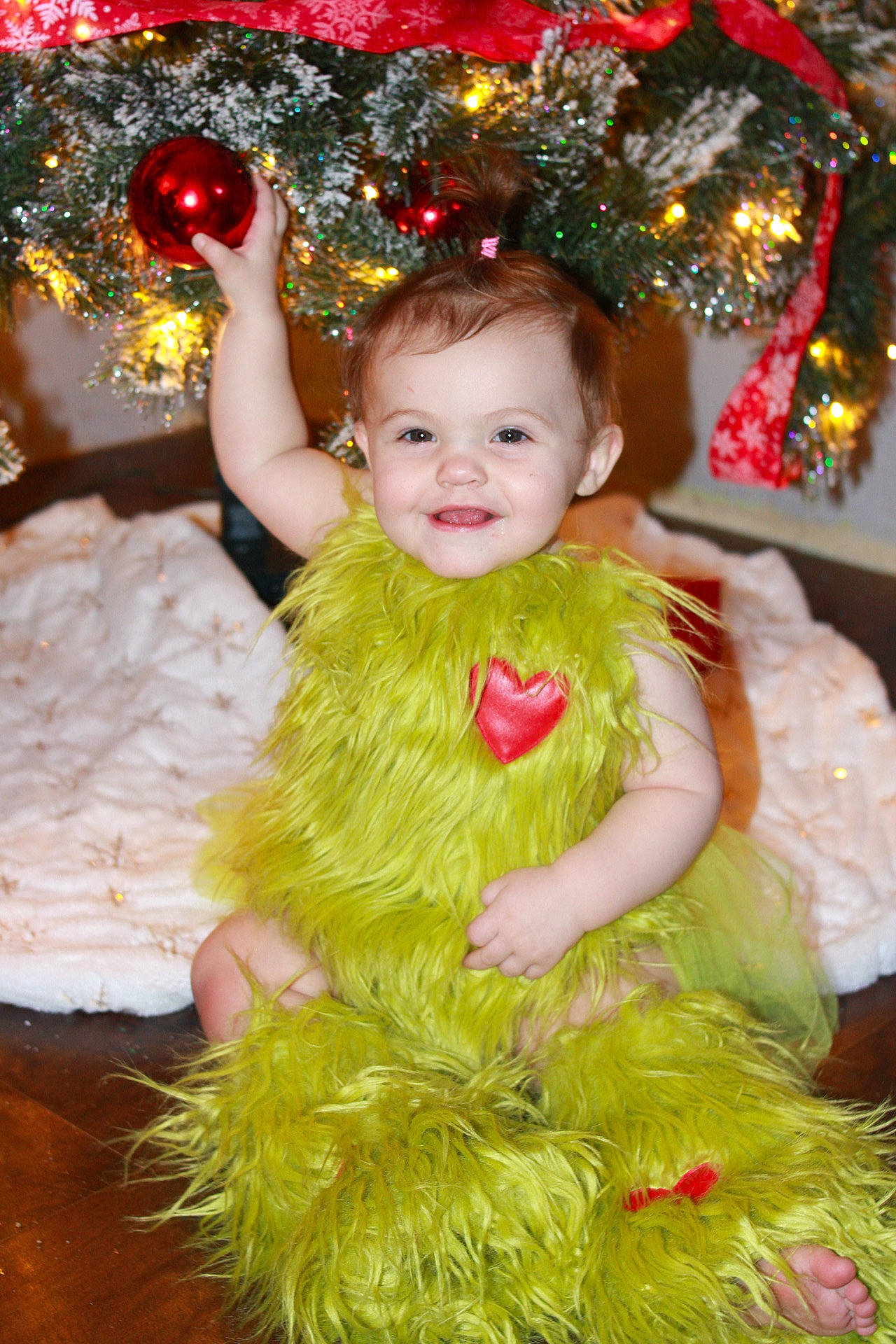 Bella is registered to the contest to win money with this photo: baby_toddler_clothing, child, christmas, christmas_decoration, christmas_ornament, christmas_tree, dress, event, face, fun, happy, head, holiday, joy, ornament, person, pink, plant, smile, toddler