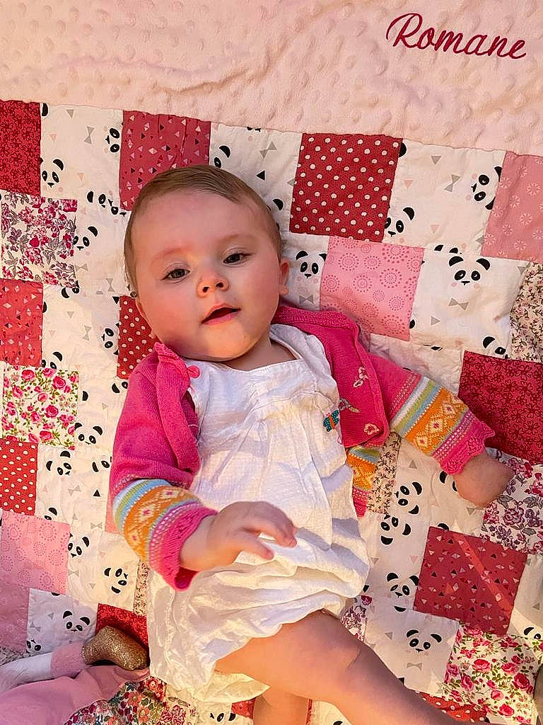 Romane a rejoint le concours — aidez-le/la à gagner de superbes lots ! baby, baby_products, baby_toddler_clothing, cheek, child, happy, linens, magenta, pattern, peach, person, pink, product, red, room, sitting, skin, sleeve, textile, toddler