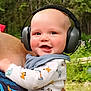 baby, headphones, smile, outdoor, child, person, forest, greenery, clothing, adult, holding, happy, cute, nature, portrait, head, earmuffs, infant, baby_clothes, daylight