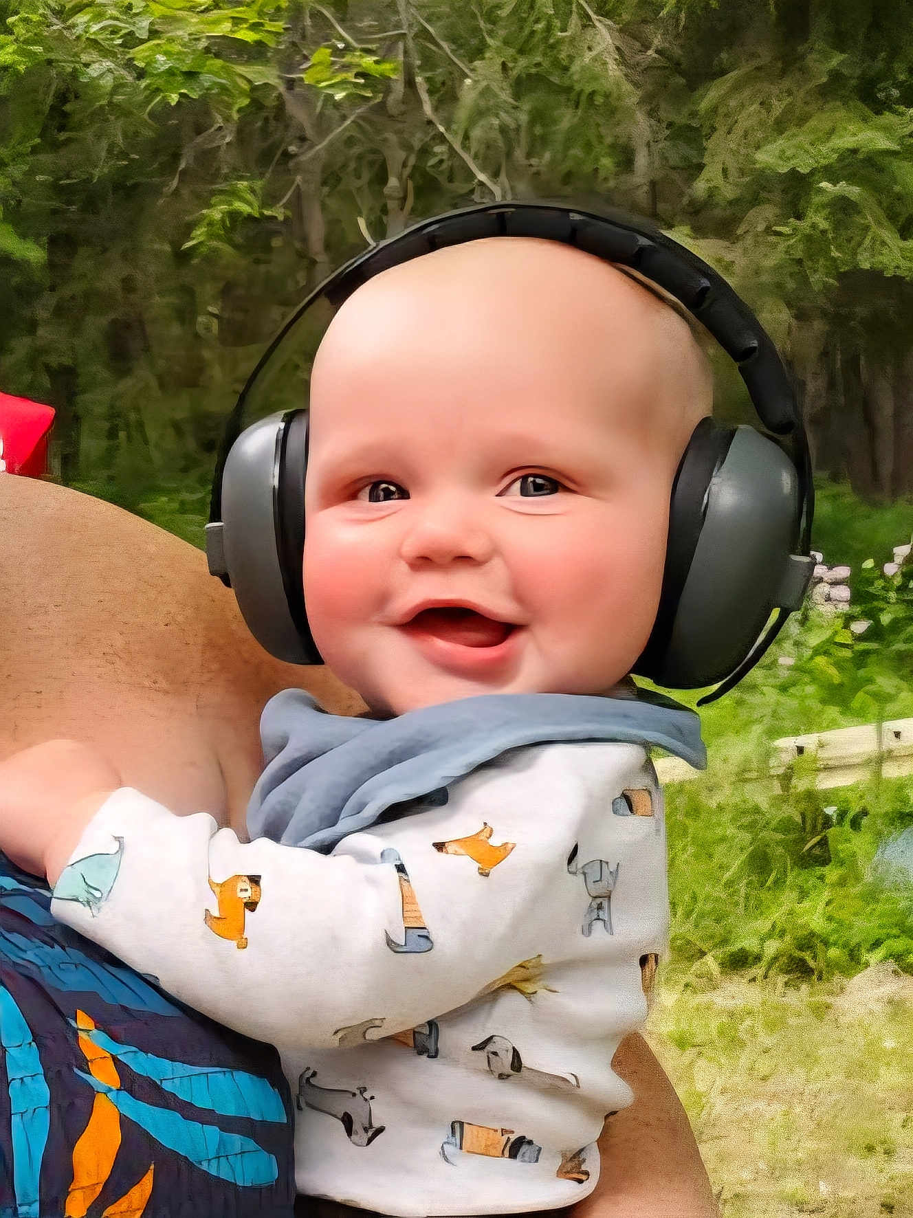 Mavrick joined the competition — help win amazing prizes! baby, headphones, smile, outdoor, child, person, forest, greenery, clothing, adult, holding, happy, cute, nature, portrait, head, earmuffs, infant, baby_clothes, daylight