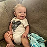 Javari is registered to the contest to win money with this photo: baby, blanket, child, clothing, comfort, couch, cozy, cute, expression, fabric, face, happy, home, indoors, infant, onesie, person, portrait, seated, smiling