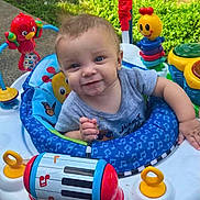 Javari is registered to the contest to win money with this photo: activity_center, baby, blue, child, clothing, colorful, cute, face, grass, green, happy, infant, outdoor, person, play, red, seat, smiling, toy, yellow