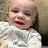 Javari is registered to the contest to win money with this photo: animal_print, baby, blue_eyes, child, closeup, couch, curly_hair, cushion, cute, face, hand, happy, indoor, infant, onesie, portrait, smiling, soft_toy, toy, young_child