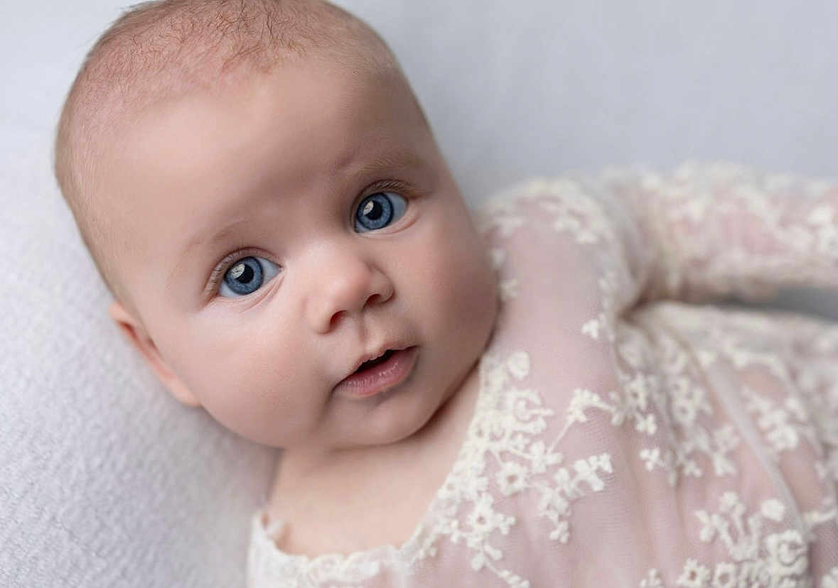 Finleigh is registered to the contest to win money with this photo: baby, infant, blue_eyes, face, portrait, close_up, lace, clothing, soft_texture, curious, cute, newborn, skin, person, lying_down, head, expression, young_child, innocence, soft_lighting