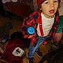 Mavrik joined the competition — help win amazing prizes! child, red_beanie, red_suspender, blue_sippy_cup, plaid_shirt, jeans, brown_shoes, dog, indoor, clutter, box, person, floor, toy, beverage_container, clothing, face, expression, standing, human