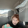 Mavrik joined the competition — help win amazing prizes! child, curly_hair, toy, car_interior, backseat, seat, headrest, window, mountain, sky, playful, tongue_out, person, seatbelt, daylight, casual, smile, vehicle, road_trip, fun