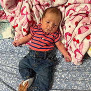 Grayson is registered to the contest to win money with this photo: baby, infant, child, striped_shirt, jeans, socks, hand, bed, blanket, pink_blanket, floral_sheet, cute, toddler_hand, sleepy, indoor, portrait, newborn, clothing, fabric, soft