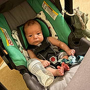 Grayson joined the competition — help win amazing prizes! baby, infant, car_seat, bottle, milk, toy, dinosaur, child, indoor, seat_belt, foot, face, person, clothing, blanket, plastic, fabric, sitting, expression, young