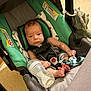baby, infant, car_seat, bottle, milk, toy, dinosaur, child, indoor, seat_belt, foot, face, person, clothing, blanket, plastic, fabric, sitting, expression, young