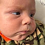 Grayson is registered to the contest to win money with this photo: baby, face, closeup, camouflage, clothing, infant, head, skin, expression, eyes, cheeks, person, portrait, young, cute, child, fashion, button, zipper, indoors