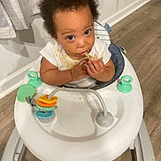 Deondre joined the competition — help win amazing prizes! baby, walker, food, indoor, curtains, flooring, stained_clothing, child, person, messy, looking_up, hands, face, eyes, hair, toy, white, plastic, seat, cute