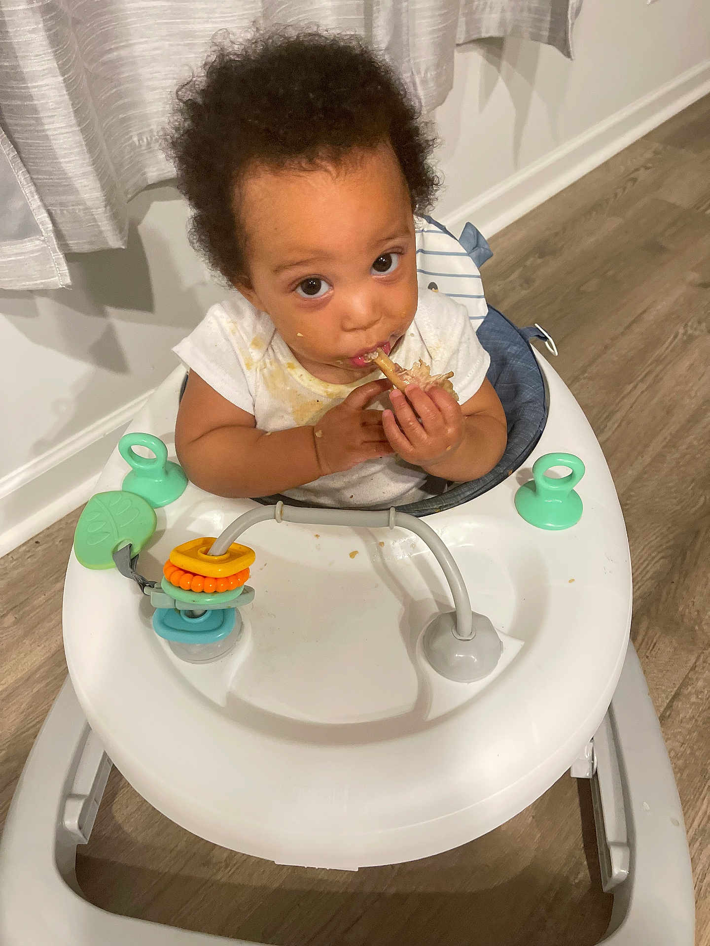 Deondre joined the competition — help win amazing prizes! baby, walker, food, indoor, curtains, flooring, stained_clothing, child, person, messy, looking_up, hands, face, eyes, hair, toy, white, plastic, seat, cute