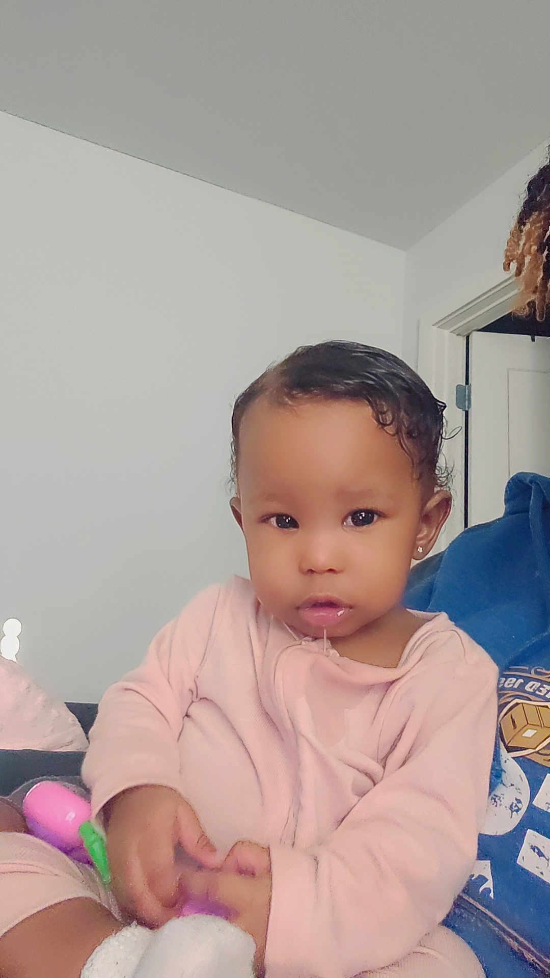 Serenity is registered to the contest to win money with this photo: toddler, child, indoor, person, pink_clothing, toy, drool, cute, baby, portrait, face, hand, sitting, young_child, earring, curly_hair, casual_wear, home, relaxed, expression