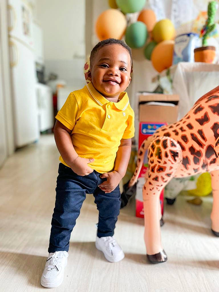 Elijah participe au concours pour gagner de l'argent avec cette photo : baby, child, door, fawn, floor, flooring, fun, giraffe, giraffidae, green, happy, joy, leisure, person, photograph, shoe, smile, snapshot, standing, toddler