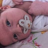 baby, pacifier, face, infant, blanket, lying_down, child, curly_hair, blue_eyes, close_up, skin, hand, white_clothing, floral_pattern, soft_lighting, indoors, portrait, cute, peaceful, newborn