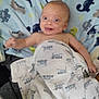 Mason is registered to the contest to win money with this photo: baby, blanket, dinosaur_pattern, smiling, face, child, blue, white, towel, happy, cute, infant, lying_down, indoors, portrait, skin, expression, eyes, mouth, head